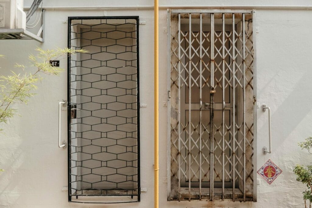 Two metal Security Grilles side by side on a white wall, one featuring a hexagonal pattern, the other with vertical bars.